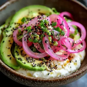 Avocado bagel topped with cottage cheese and pickled onions.