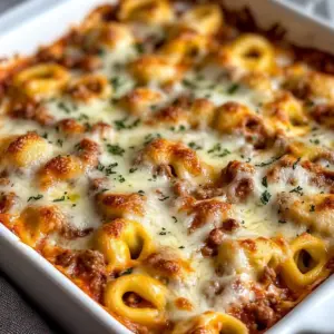 Cheesy Tortellini Bake topped with meat sauce in a baking dish