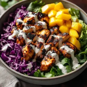 Plate of jerk chicken served with colorful mango slaw and herbs