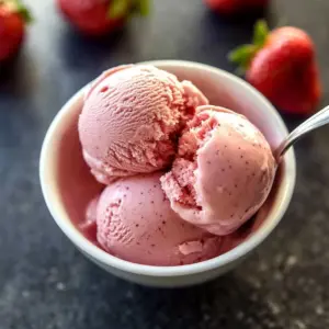 No-churn strawberry ice cream in a bowl topped with fresh strawberries